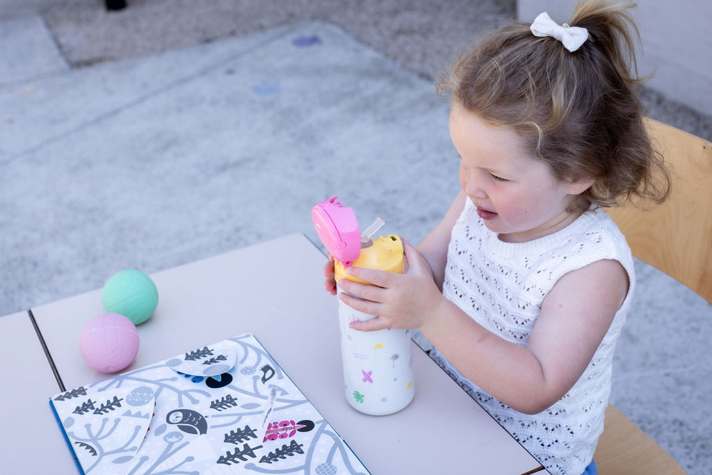 Drinking from a cup with a straw starting at 9 months